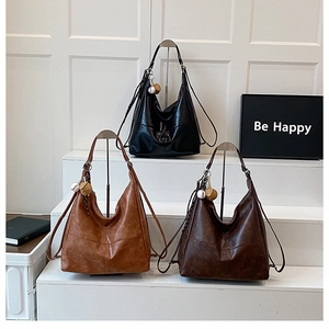 Detalle de tres bolsos tote de cuero vintage con dijes de béisbol en un soporte
