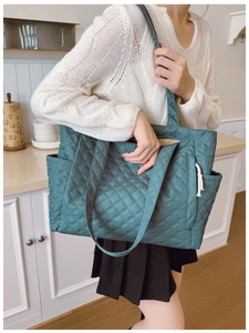 Close-up of diamond quilted tote bag in dark teal fabric with side pocket detail