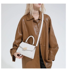 Détail du sac bandoulière blanc matelassé avec fermoir doré sur un mannequin en cuir