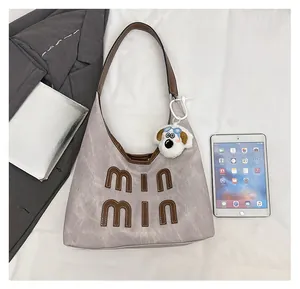 Detail view of large grey tote bag with letter patches and cute cartoon dog charm