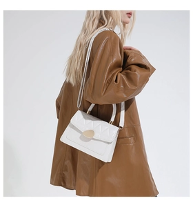 Détail du sac à bandoulière en similicuir matelassé blanc avec boucle dorée sur mannequin