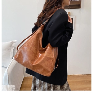 Bolso tote retro de cuero marrón de gran capacidad mostrado en el hombro de una modelo