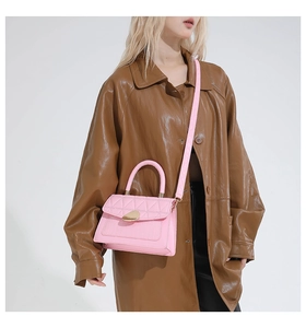 Détail d'un sac à main matelassé rose avec fermoir doré sur un fond de trench-coat marron