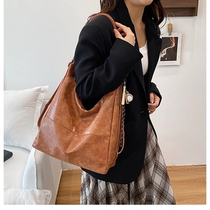 Detalle de bolso tote vintage marrón con textura de cuero y colgante de béisbol