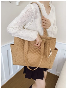 Close-up of a large quilted tote bag in light khaki nylon with side pocket detail