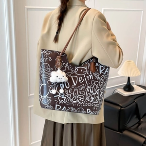Brown graffiti tote bag with cat patterns and cloud pendant shown in a modern home setting