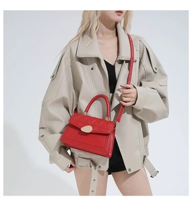 Détail d'un sac rouge en cuir croco avec fermoir doré et bandoulière réglable