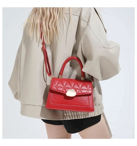 Détail du sac rouge à motif croco avec fermoir doré porté à l'épaule par le mannequin