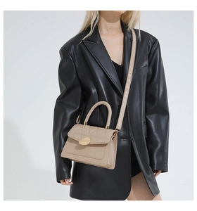 Détail d'un sac matelassé beige en simili cuir avec fermoir doré et poignée