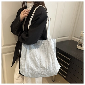 Detail of light blue pleated tote bag showing the reinforced strap and fashion patch