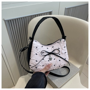 Détail du tissu plissé rose avec broderie nœud noir et pendentif cœur sur le sac