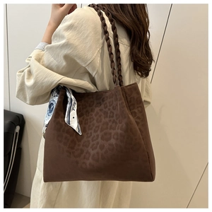 Detail of leopard print tote bag with thick woven rope handle and silk scarf accessory