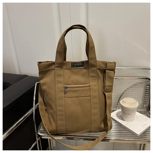 Detail of khaki canvas tote bag showing fashion instinct label and metal zipper pocket