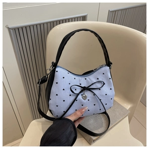 Détail du sac en toile à rayures bleues avec motifs de cœurs et nœud noir