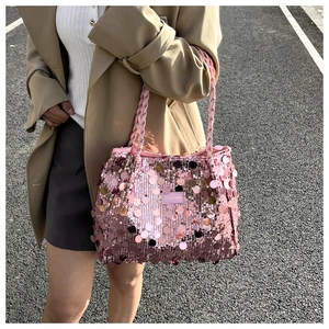 Detail of a pink oversized sequin tote bag with woven handles shown in an outdoor setting