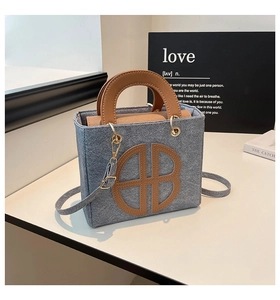 Dettaglio della borsa a tracolla in feltro grigio con inserti in pelle marrone e oro
