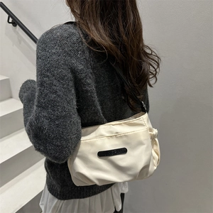 Minimalist beige nylon crossbody tote bag with pleated side details and adjustable strap