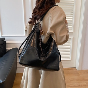 Bolso hobo grande minimalista de cuero suave negro con detalle de borla trenzada