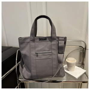 Detail of grey canvas tote bag featuring front zip pocket and Fashion Instinct logo
