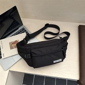 Marsupio monospalla nero in nylon da uomo posizionato accanto a un laptop su scrivania