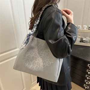 Fashionable grey leopard print tote bag with floral scarf handle worn on shoulder