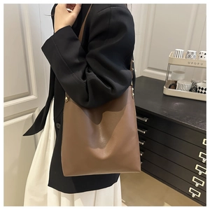 Close-up of minimalist brown leather tote bag with slim shoulder strap for office commuting