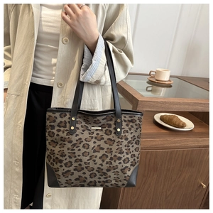Close-up of leopard print canvas tote bag with gold metal studs and leather reinforced base