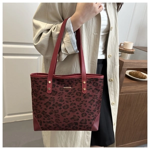 Close-up of leopard print tote bag with burgundy leather trim and gold logo plaque