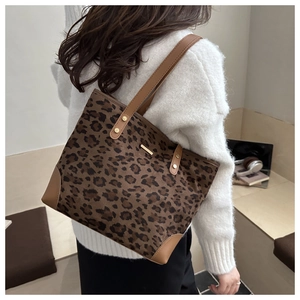 Detail of leopard print tote bag with brown leather handles and golden metal hardware