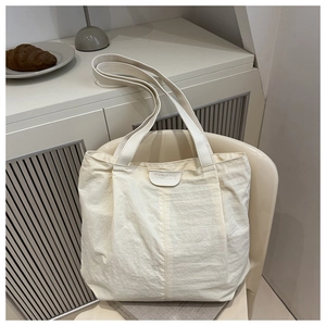 Détail du sac cabas en tissu blanc crème avec étiquette mode sur une chaise douillette