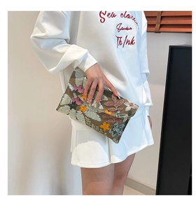 Detail of floral embroidery and sequins on the envelope clutch bag with chain strap