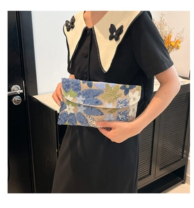 Detail of handmade floral embroidery with sequins on an elegant envelope clutch bag