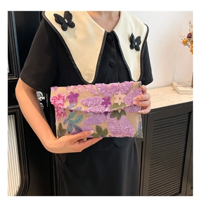 Chic envelope clutch featuring vibrant floral sequins carried by model in black outfit