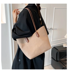 Close-up of beige pebble leather tote bag with contrasting brown shoulder straps on model