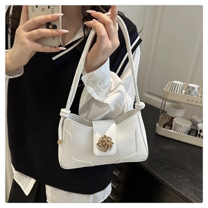 Close-up of white leather handbag featuring a golden floral clasp on a shoulder bag strap