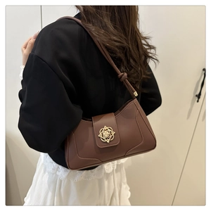 Detail of vintage brown shoulder bag with ornate gold floral buckle and fine stitching