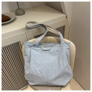 Détail du sac cabas plissé bleu clair avec patch FASHION sur fond esthétique doux