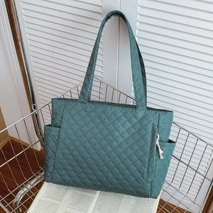 Quilted dark green tote bag with large capacity and quilted diamond pattern in a shopping cart