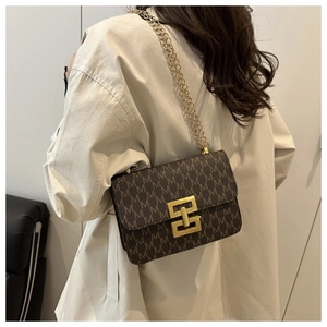 Detail of vintage square bag with M-pattern print and gold metal clasp on shoulder strap