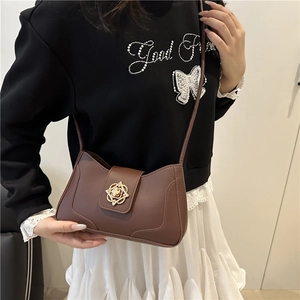 Brown retro shoulder bag with a gold floral twist lock worn by a model in casual wear