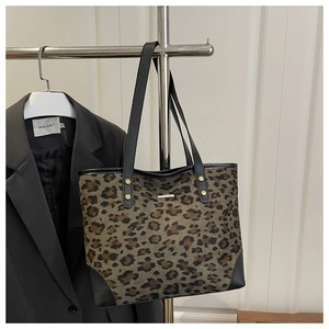 Detailed view of leopard print tote bag with black handles and gold rivet accents