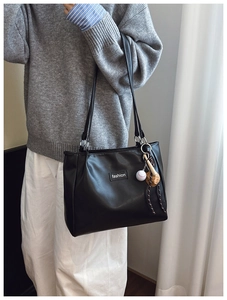 Detail of black tote bag featuring fashion label and decorative baseball theme charm