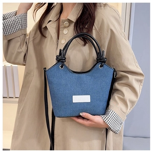 Gros plan du sac seau en denim montrant la texture, les anses nouées et l'étiquette