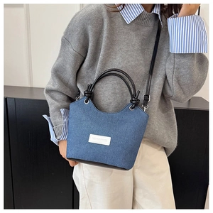 Détail du sac seau en jean bleu avec étiquette de mode et poignée anneau noire sur modèle