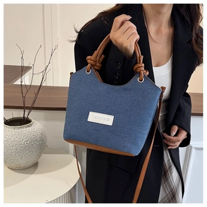 Détail du sac seau en denim avec contraste en cuir marron et bandoulière nouée réglable