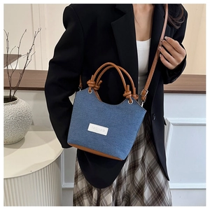 Détail du sac à bandoulière en denim avec poignées en cuir brun et nœuds décoratifs