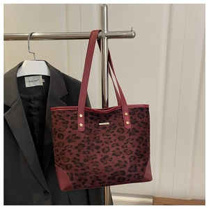 Macro detail of leopard print faux leather tote bag with red trim and gold studs