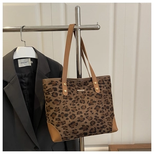 Detail of leopard print tote bag featuring brown leather trim and golden rivets