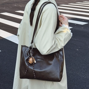 Vintage dark brown large capacity tote bag with bear charm on a street background