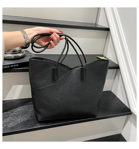 Detail of black tote bag featuring premium lychee grain texture and elegant V-shaped fold design